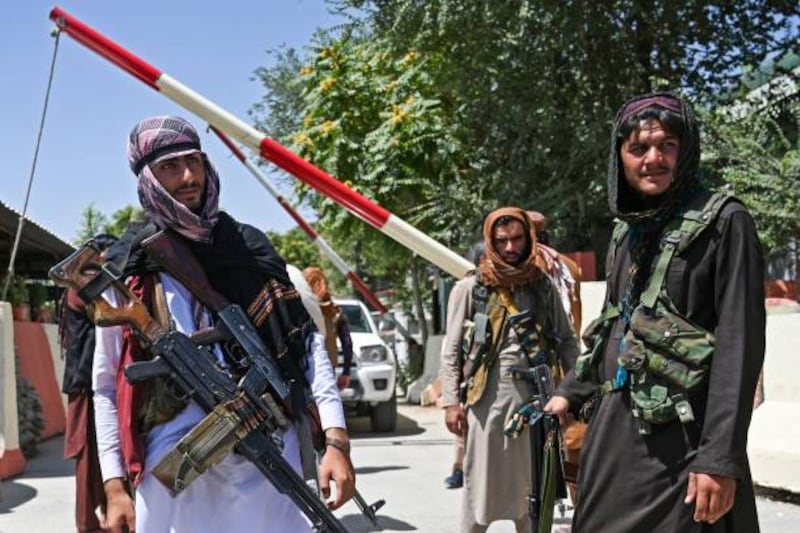Taliban fighters stand guard along a roadside near Zanbaq Square in Kabul.