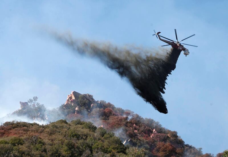 A helicopter drops water on brush burning near Pepperdine University as the Woosley Fire continues to burn in Malibu. EPA