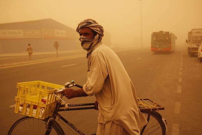 A Pakistani covers his face with a head scarf while crossing the street as a sandstorm rages in Dubai. Antonie Robertson / The National