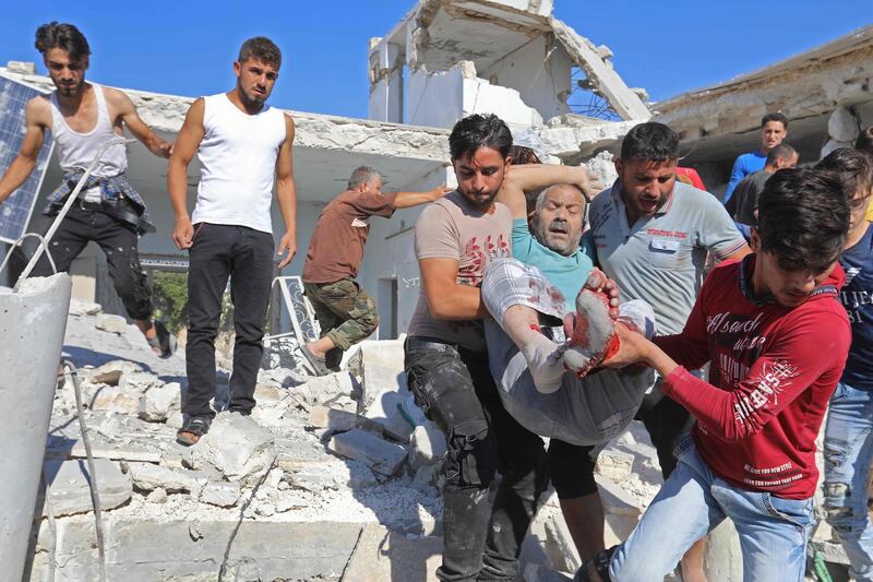 Syrian civilians help carry away a victim from the rubble of a building following reported air strikes by pro-regime forces on Maaret al-Numan in Syria's northwestern Idlib province on July 23, 2019.  / AFP / Omar HAJ KADOUR
