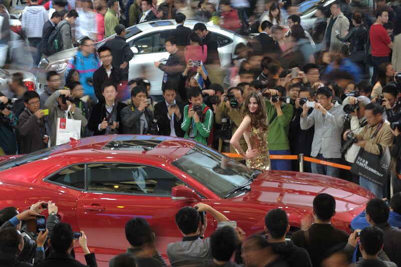 A model poses next to a Chevrolet Camero on the opening day of the Shanghai auto show on April 21, 2013. Chinese buyers swarmed around hundreds of vehicles at the Shanghai auto show at its opening highlighting the importance of the world's largest car market to manufacturers. AFP PHOTO/Peter PARKS

