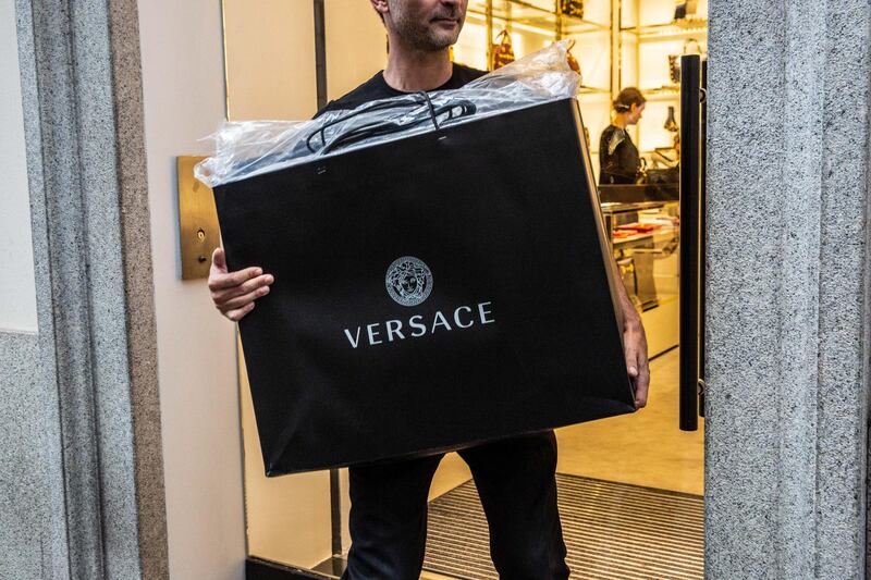 A man carries a Gianni Versace SpA branded shopping bag at a store in Milan, Italy, on Monday, Sept. 24, 2018. Handbag maker Michael Kors Holding Ltd. is nearing an agreement to buy Versace after the Italian fashion house known for its baroque designs drew interest from several suitors, people familiar with the plans said. Photographer: Francesca Volpi/Bloomberg