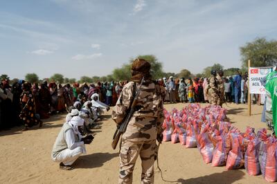 A soldier stands by as Sudanese women who fled the violence in their country wait to receive food supplies from a Turkish aid group near the border between Sudan and Chad. Reuters 