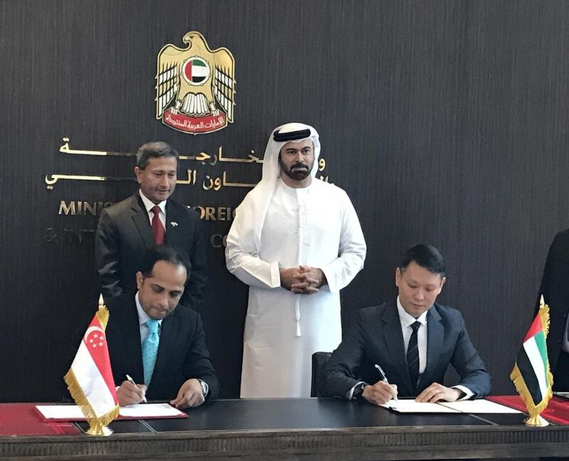Sopnendu Mohanty, the chief fintech Officer of Monetary Authority of Singapore, left, and Richard Teng, the chief executive of FSRA of ADGM sign the agreement in the presence of Mohammed Al Gergawi, centre, Minister of Cabinet Affairs. Courtesy Abu Dhabi Global Market