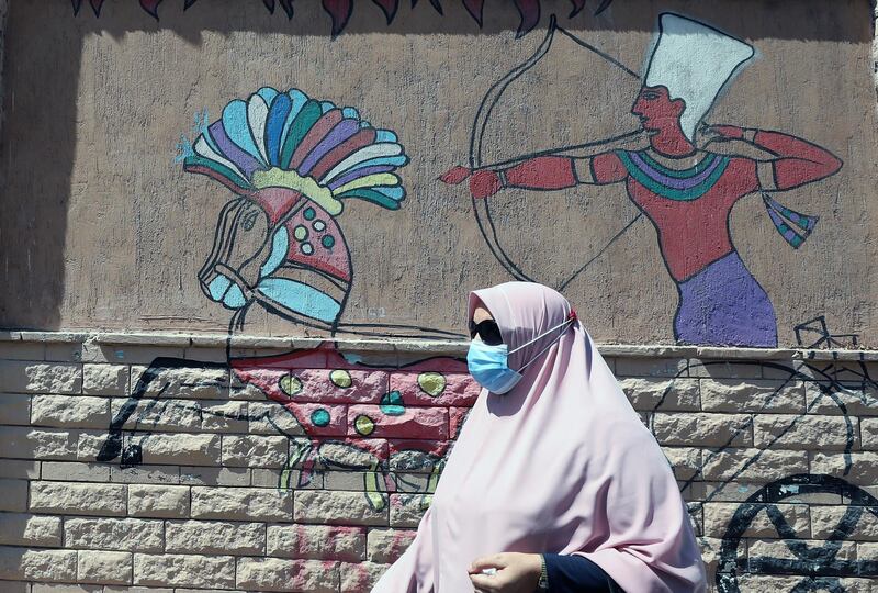 A woman wearing protective face mask walks near wall painting on a street in Cairo, Egypt. Countries around the world are taking increased measures to stem the widespread of the coronavirus.  EPA