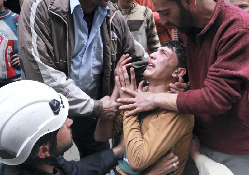 A man is comforted by a rescue worker and others following a reported air strike by government forces in which a fellow rescue worker was killed on March 9, 2014 in the northern city of Aleppo. More than 140,000 people have been killed in Syria since the start of a March 2011 uprising against the Assad family's 40-year rule AFP PHOTO / BARAA AL-HALABI (Photo by BARAA AL-HALABI / AFP)
