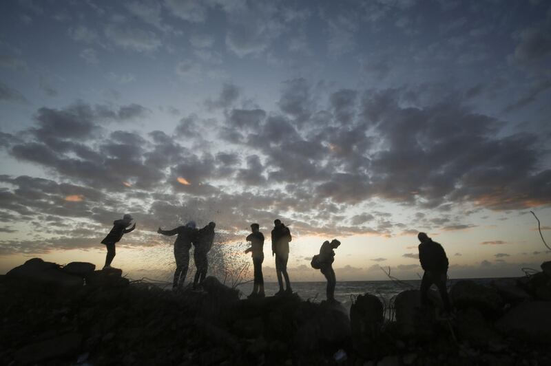 Palestinians stand on rocks at sunset on the Mediterranean coast in Gaza City. AFP