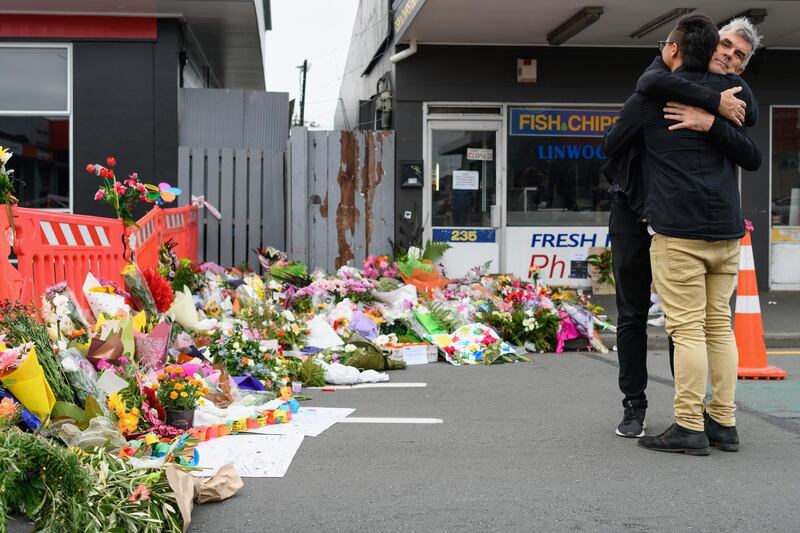 Strangers comfort each other in front of flowers and condolences near Linwood mosque in Christchurch. Getty Images