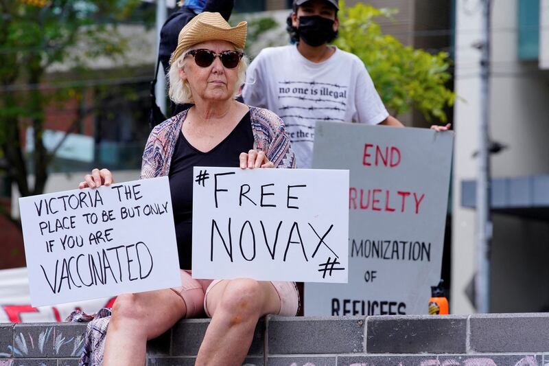 A protestor holds signs outside Park Hotel, where Serbian tennis player Novak Djokovic is believed to be living, in Melbourne. AFP