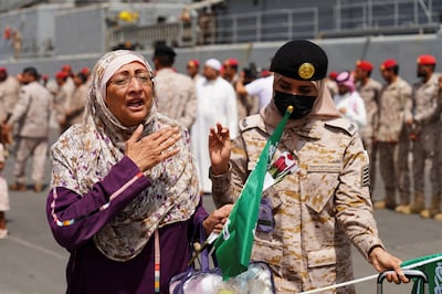 A Royal Saudi Naval Forces officer helps an evacuee as she disembarks at  Jeddah. Reuters
