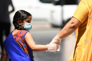 A mother and daughter wear gloves and face masks as they walk in Dubai. AFP