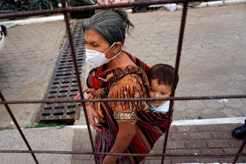 A woman carries a baby as she lines up to receive a hot meal from municipal workers at Ciudad Peronia neighborhood in Villa Nueva municipality in Guatemala. AFP