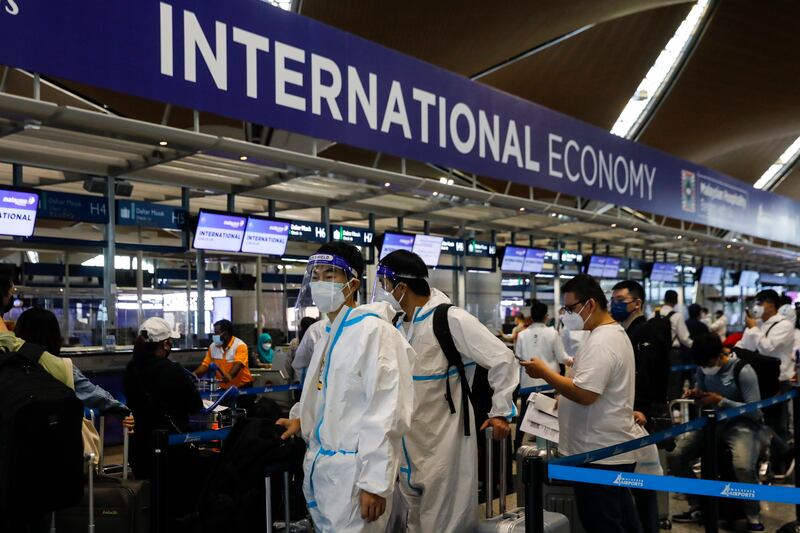 Travellers wearing personal protective equipment wait for their turn at a flight ticket counter at Kuala Lumpur International Airport, Malaysia. EPA