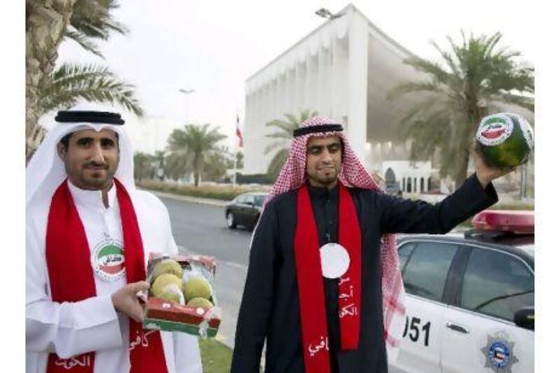 Two men from the Kuwaiti youth movement Kafi (Enough) hold watermelons as part of a protest calling for the resignation of Kuwait's prime minister.