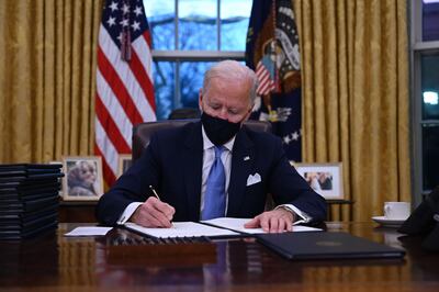 TOPSHOT - US President Joe Biden sits in the Oval Office as he signs a series of orders at the White House in Washington, DC, after being sworn in at the US Capitol on January 20, 2021.  US President Joe Biden signed a raft of executive orders to launch his administration, including a decision to rejoin the Paris climate accord. The orders were aimed at reversing decisions by his predecessor, reversing the process of leaving the World Health Organization, ending the ban on entries from mostly Muslim-majority countries, bolstering environmental protections and strengthening the fight against Covid-19. / AFP / Jim WATSON
