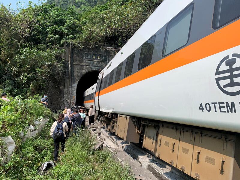 People walk next to a train which derailed in a tunnel north of Hualien, Taiwan, in this handout image provided by Taiwan's National Fire Agency. Reuters