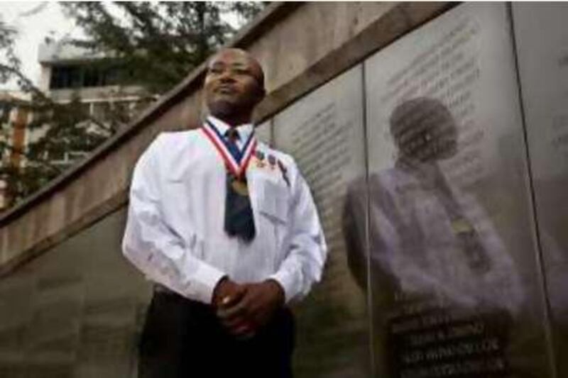 Joash Okindo stands by the memorial at the site of the 1998 US Embassy bombing. Joash was a  guard at the gate of the US Embassy when terrorists drove up with the bomb. He stopped them from getting into the underground parking lot, which would have been a much worse explosion. He was awarded a medal by the State department and is considered a hero.  *** Local Caption ***  IMG_4535-Edit.JPG