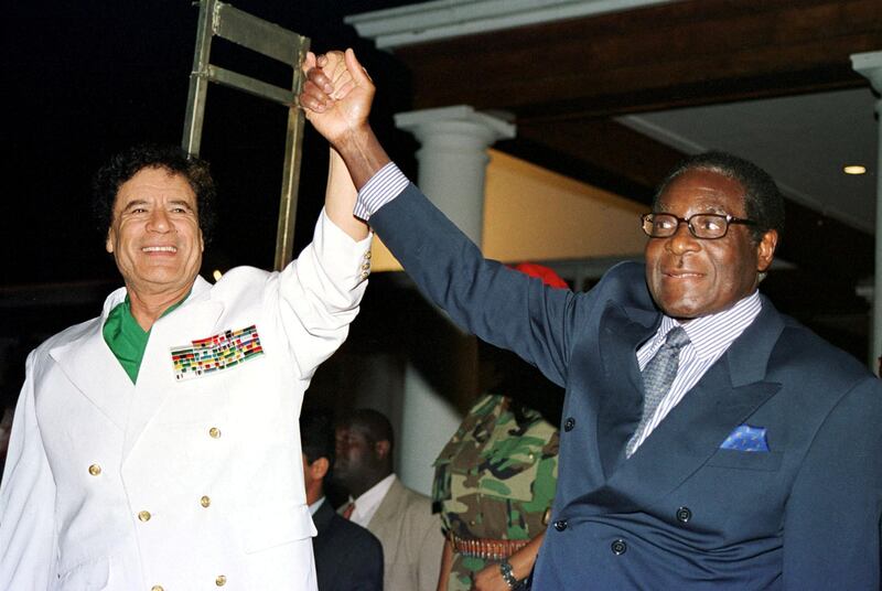 FILE PHOTO: Libyan leader Colonel Muammar Gaddafi (L) and Zimbabwe President Robert Mugabe greet supporters outside State House in Harare, Zimbabwe July 12, 2001. REUTERS/Stringer/File Photo