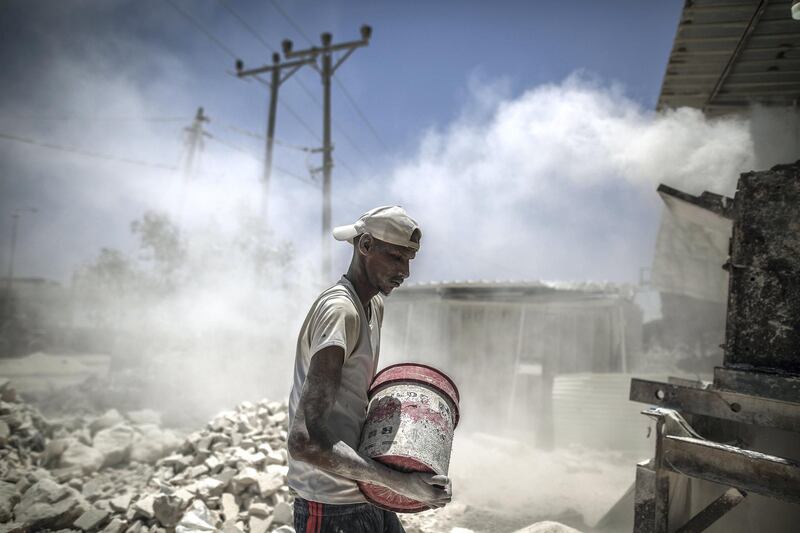 Workers with the rubble of buildings destroyed during the May rocket attacks. Sanad Latefa for The National