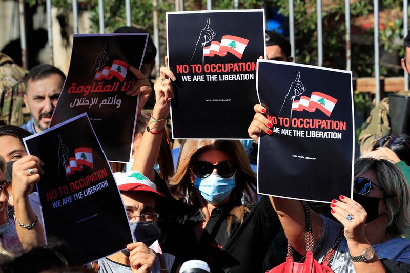 Activists supporting the families of those who were killed in the port blast last year hold placards during a protest in solidarity with Judge Tarek Bitar. AP