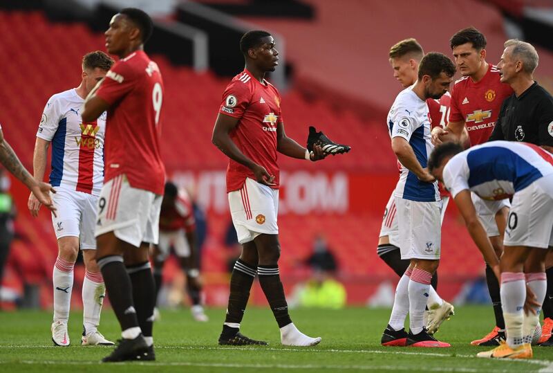 Manchester United midfielder Paul Pogba holds his boot as he talks to referee Martin Atkinson after he went down in the box. AFP