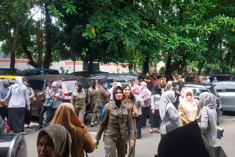 People wait outside a government building that was evacuated in Makassar, Indonesia, after the earthquake. AP