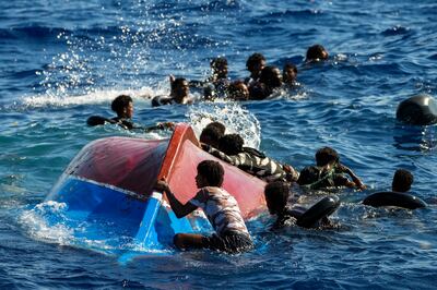 Migrants next to their overturned boat during a rescue operation in the Mediterranean south of the Italian island of Lampedusa on Thursday. AP