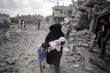A Palestinian woman passes by rescuers inspecting the rubble of destroyed houses after Israeli strikes in Rafah refugee camp, southern Gaza Strip. AP 