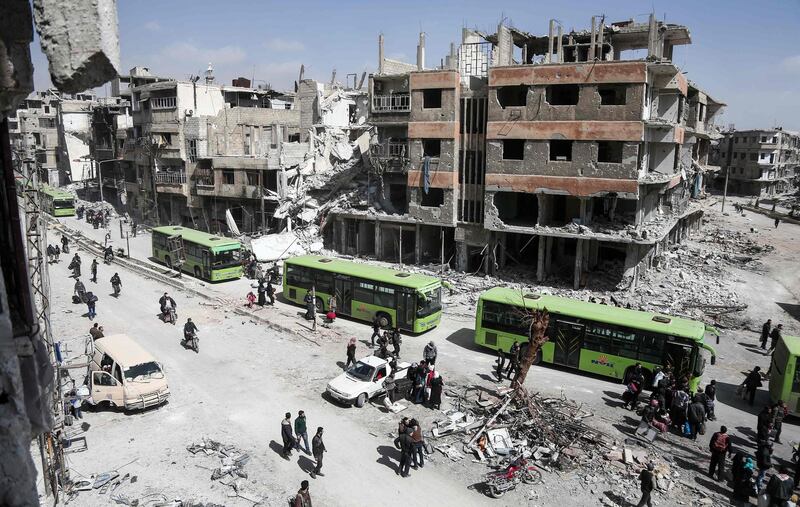 TOPSHOT - Syrian civilians and rebel fighters prepare to embark aboard buses during the evacuation from the town of Arbin in the Eastern Ghouta region on the outskirts of the capital Damascus on March 25, 2018 after a deal was struck with the regime.
The deal is expected to see some 7,000 people bussed from Arbin and Zamalka towns and the district of Jobar to a rebel-dominated part of northern Syria. / AFP PHOTO / Abdulmonam EASSA