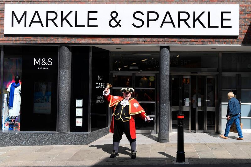 A town cryer rings his bell outside a branch of retailer Marks and Spencer, that has changed the name sign on the facade to Markle and Sparkle in honour of the Royal Wedding of Britain's Prince Harry and Meghan Markle, in Windsor on May 18, 2018, the day before the wedding.  Britain's Prince Harry and US actress Meghan Markle will marry on May 19 at St George's Chapel in Windsor Castle. / AFP / Paul ELLIS
