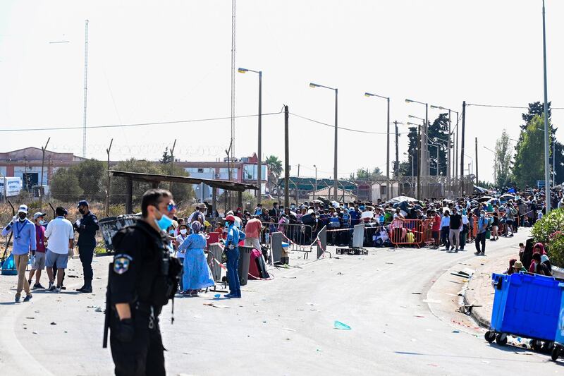 Asylum seekers wait in a line with their belongings as refugees and migrants from the destroyed Moria camp wait to enter into the new temporary camp near Kara Tepe on Lesbos island, Greece.  EPA