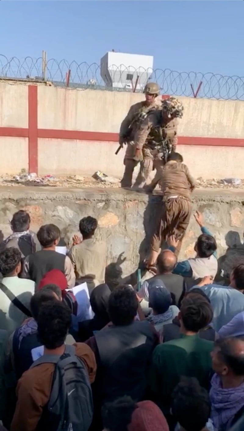 People desperate to flee Taliban-ruled Afghanistan try and climb over the wall to enter the airport. Reuters