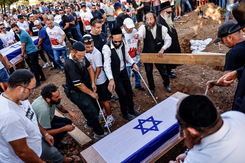 Men lower one of the coffins during the funeral of British-Israelis Lianne Sharabi and her daughters Noiya Sharabi, 16, and Yahel Sharabi, 13, in Kfar Harif, Israel. EPA