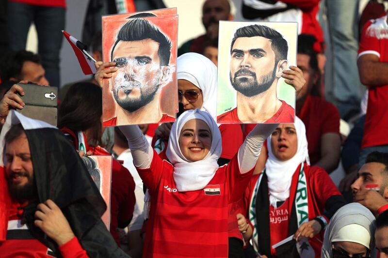 A supporter holds images of Syria's Omar Al-Soma and Omar Khrbin. AFP