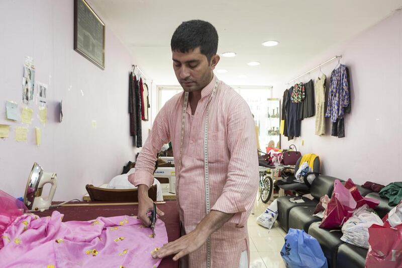 Tailor Irfan Khan cuts the hem of a dress at Modern Ladies Tailoring in Satwa ahead of Eid Al Fitr. New clothes are traditionally worn during the Eid celebrations. Antonie Robertson / The National