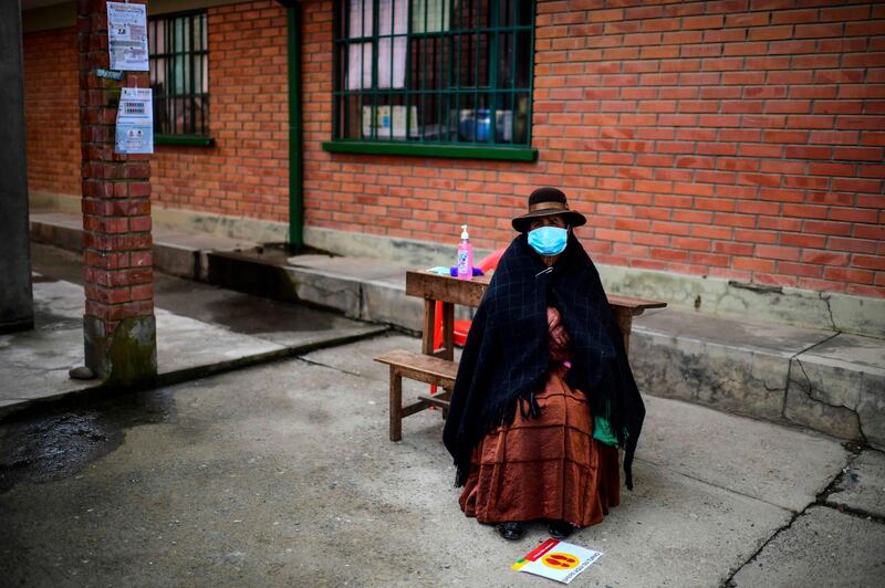 An indigenous woman sits on a bench as she waits at a polling station in Huarina, Bolivia, during the presidential election on Sunday. AFP
