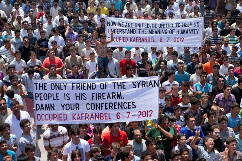 Syrian protesters hold banners referring to the international conference on the Syrian crisis being held in Paris during a demonstration after Friday prayers in Kafranbel on July 06, 2012. AFP