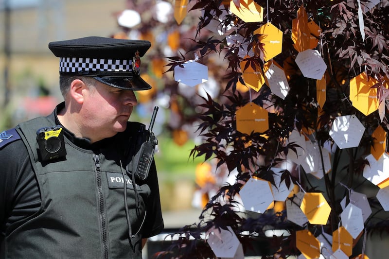 A police officer looks at messages on a tree of hope head of The Manchester Arena National Service of Commemoration. Getty