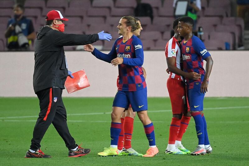 An Atletico Madrid staff member greets former player Antoine Griezmann at the end of the the 2-2 draw with Barca on June 30, 2020. Griezmann came on as a substitute in the last minute. AFP