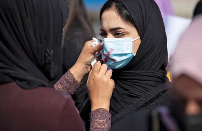 A demonstrator uses lipstick to cross out the mask of another protester as they attend a rally for International Women's Day in the southern Iraqi city of Basra. Photo: AFP