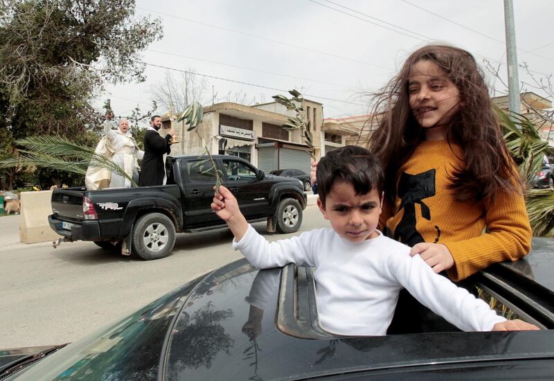 Children hold olive branches as they look out from the sunroof of a car to be blessed by priests to celebrate Palm Sunday, amid the lockdown to contain the coronavirus in Marjayoun, southern Lebanon. Reuters