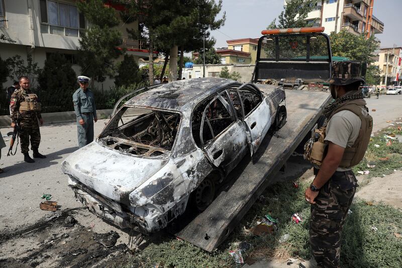 Security personnel inspect a damaged vehicle where rockets were launched in Kabul, Afghanistan. AP