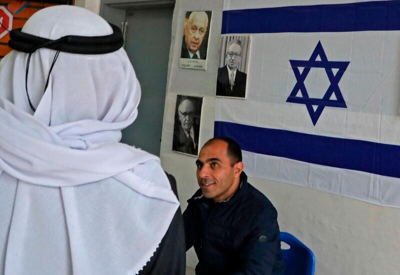 An Arab-Israeli man arrives at a poling station, decorated with portraits of Israeli politicians, to cast his ballot for the parliamentary election in the Bedouin town of Rahat near the southern Israeli city of Beersheba on March 2, 2020. AFP