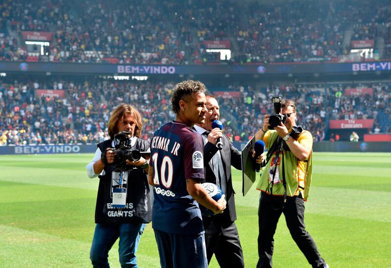 Paris Saint-Germain's Brazilian forward Neymar poses with a ball during his presentation to the fans at the Parc des Princes stadium in Paris on August 5, 2017. 
Brazil superstar Neymar will watch from the stands as Paris Saint-Germain open their season on August 5, 2017, but the French club have already clawed back around a million euros on their world record investment. Neymar, who signed from Barcelona for a mind-boggling 222 million euros ($264 million), is presented to the PSG support prior to his new team's first game of the Ligue 1 campaign against promoted Amiens. / AFP PHOTO / ALAIN JOCARD