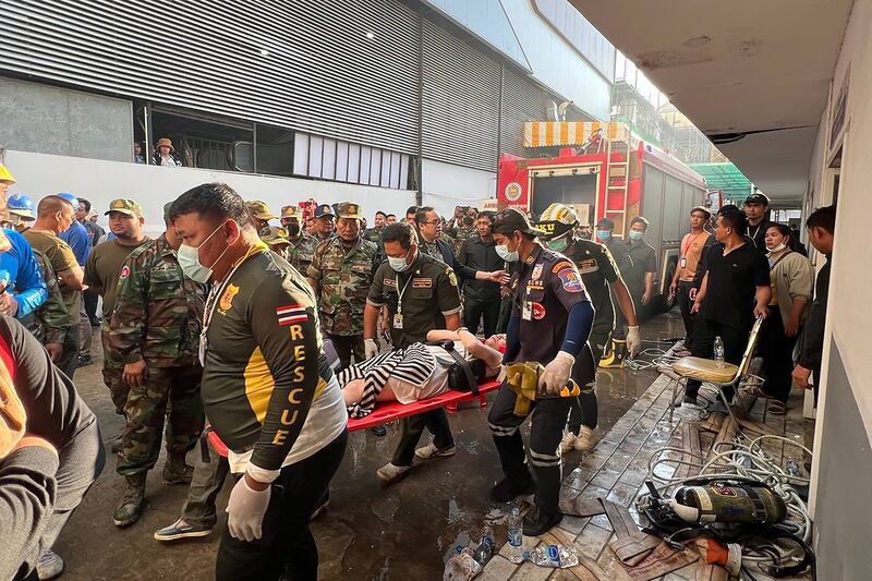 Rescue workers carry a person injured during the fire. AFP