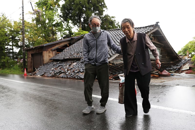 Residents of Suzu city pass by a house that collapsed when a 6. 5 magnitude earthquake hit Japan's Ishikawa prefecture. AFP