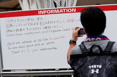 A spectator takes photos of an information board announcing the cancellation of all practice and qualifying sessions for the Japanese Grand Prix scheduled for Saturday due to the approach of Typhoon Hagibis. Reuters