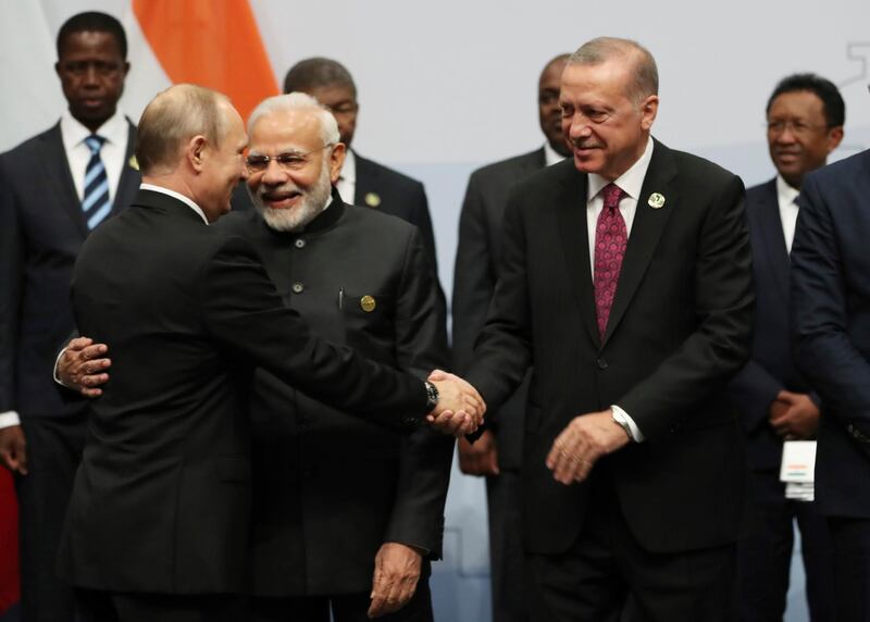 Turkey's President Recep Tayyip Erdogan, right, shakes hands with Russian President Vladimir Putin before they pose for a group picture at the emerging national economies (BRICS) summit meeting in Johannesburg, South Africa, Friday, July 27, 2018. Indian Prime Minister Narendra Modi stands between Putin and Erdogan.(Presidential Press Service via AP, Pool)