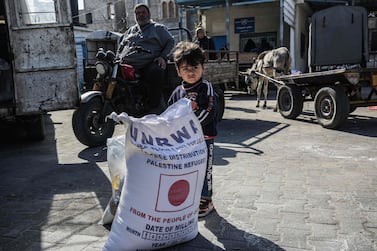 A child stands next to a sack flour provided by the UN Relief and Works Agency in the Khan Yunis Palestinian refugee camp in southern Gaza on February 2, 2020. AFP