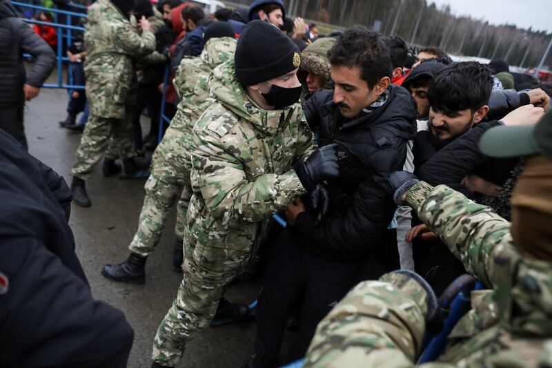 Belarusian servicemen try to control the crowd as migrants try to receive food near the border. Reuters
